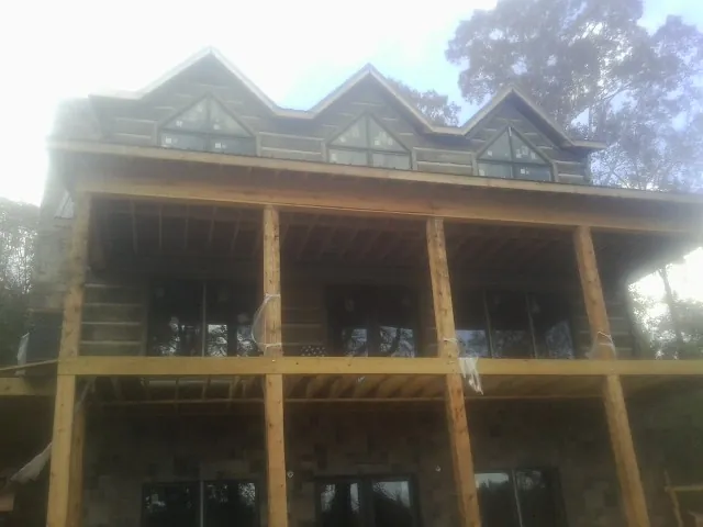 Dormers and porch framing on a large log home under construction — Roof Coating work by our crew in Brockton